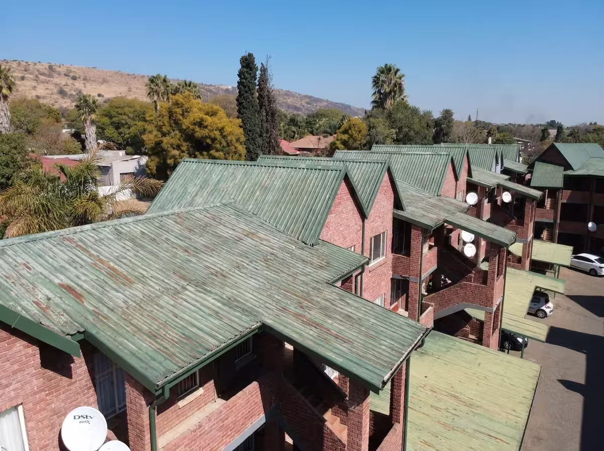 Large complex roof before repainting showing faded and patchy surface — Centurion